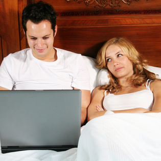 frustrated woman in bed with man and his laptop